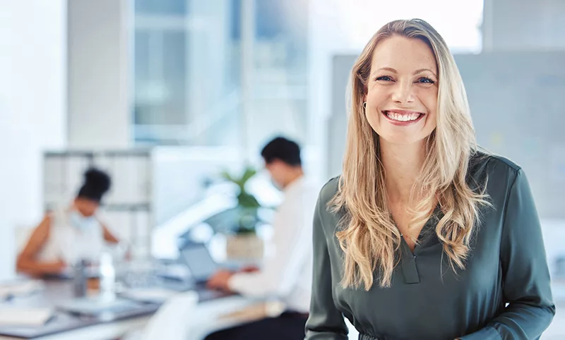 this woman smiles because she uses a no-code application that makes her life easier at the office